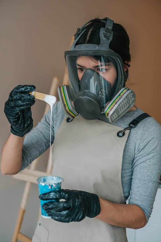 man wearing a respirator mixing resin in a cup 