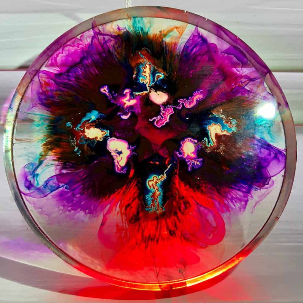 clear resin coaster with alcohol ink used to create a neon effect 