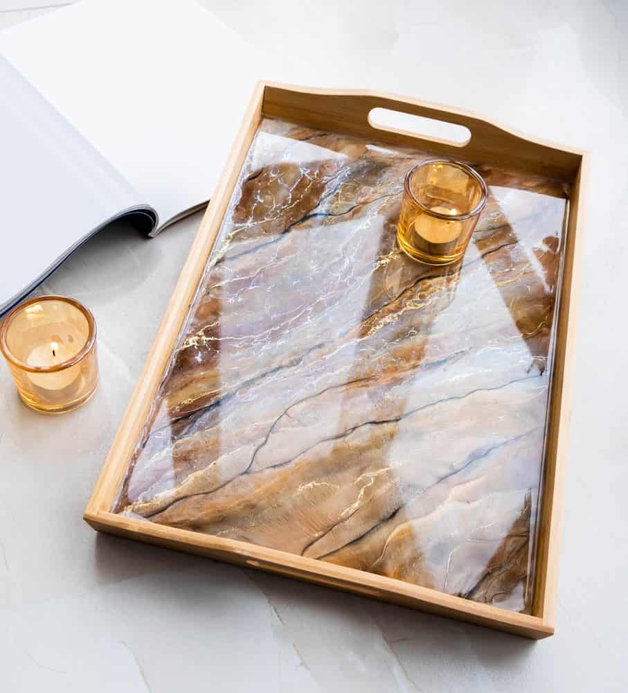 Sustainable Resin Disposal: Eco-Friendly Ways to Handle Leftover Resin 5 A wooden serving tray with a marbled resin surface, holding a glass and a candle.