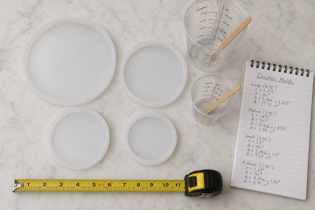 A top-down view of four various-sized translucent silicone coaster molds laid out on a marble surface. The scene includes a yellow measuring tape showing sizes from 2.5 to 4.75 inches, two plastic mixing cups with wooden stir sticks, and a spiral notepad detailing the mathematical area calculations for each mold size using the formula $A = \pi r^2$.