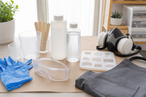Resin PPE for beginners with nitrile gloves, goggles, respirator, apron, and resin supplies.