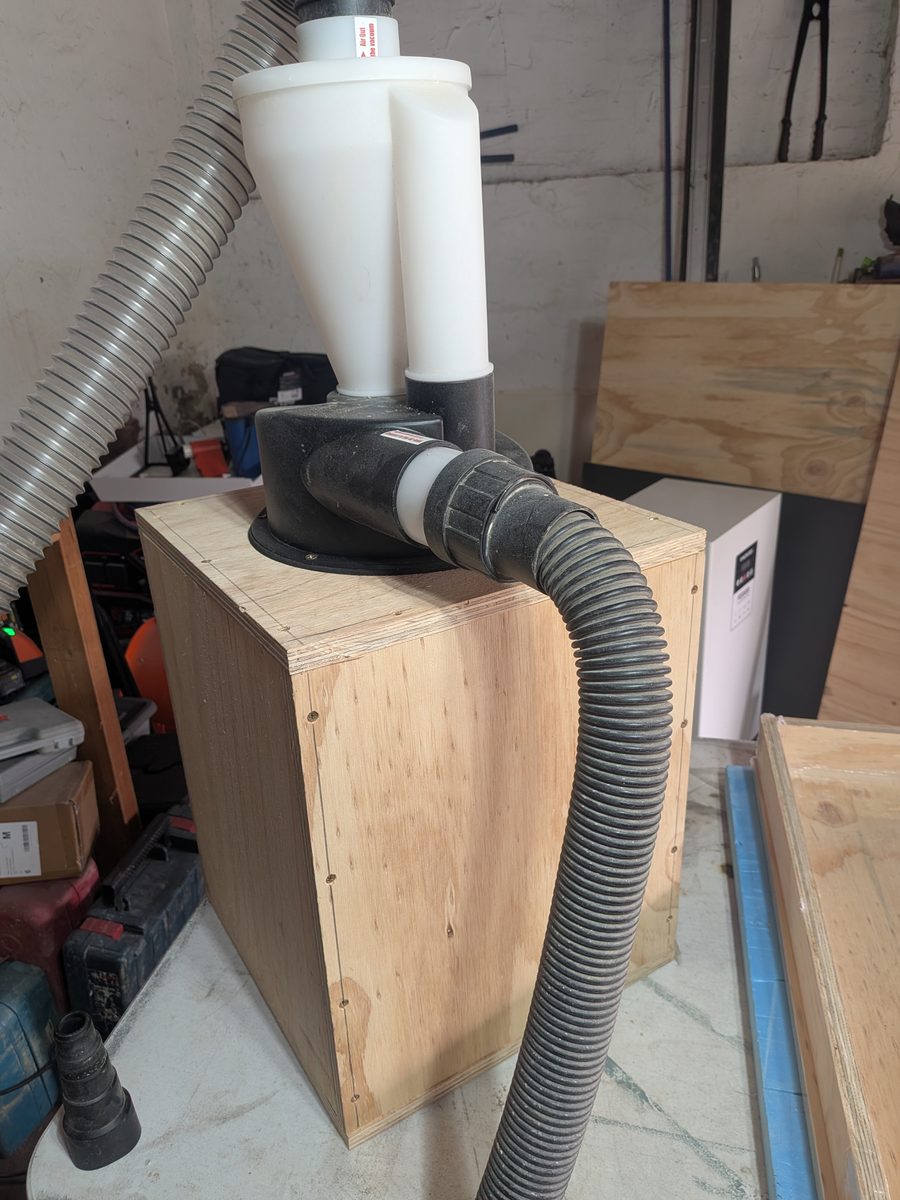 Cyclone dust separator mounted on top of a screwed plywood bin, with the tool hose connected to the inlet
