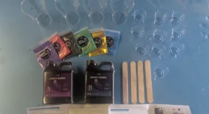 Let’s Resin epoxy starter kit laid out: Part A and Part B bottles, six mica powder bags, four graduated mixing cups, ten small pour cups and four wooden stir sticks