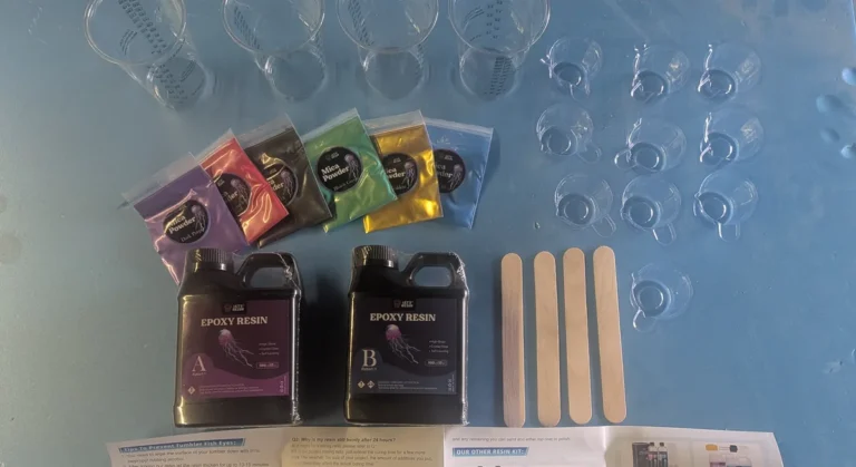Let’s Resin epoxy starter kit laid out: Part A and Part B bottles, six mica powder bags, four graduated mixing cups, ten small pour cups and four wooden stir sticks