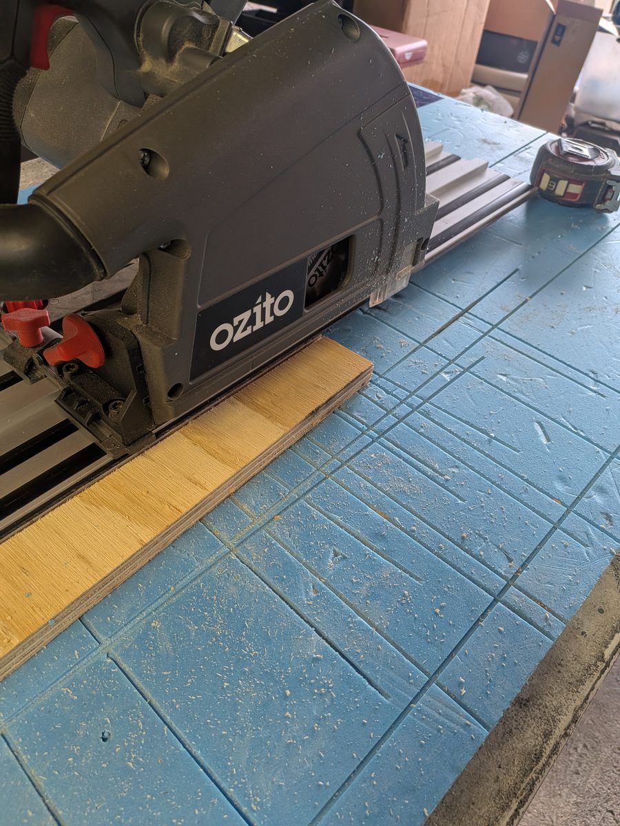 The same track saw cut through plywood with dust extraction connected, leaving only a light scatter of chips