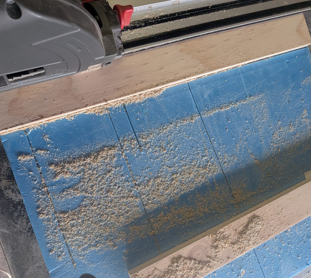 Sawdust spread across a foam cutting board after one track saw cut through plywood without dust extraction