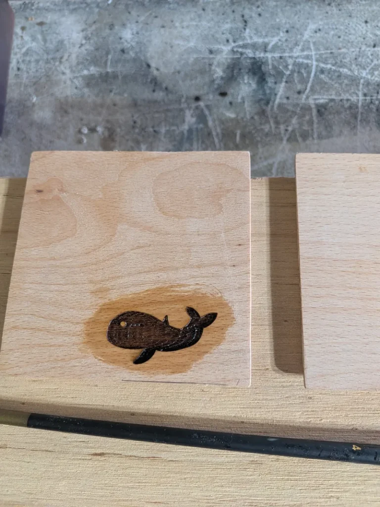 Seal coat of epoxy that ran past an engraved whale and darkened the bare beech into a halo