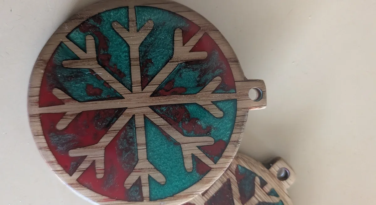 Close-up of a finished wooden snowflake ornament with glossy red and teal resin