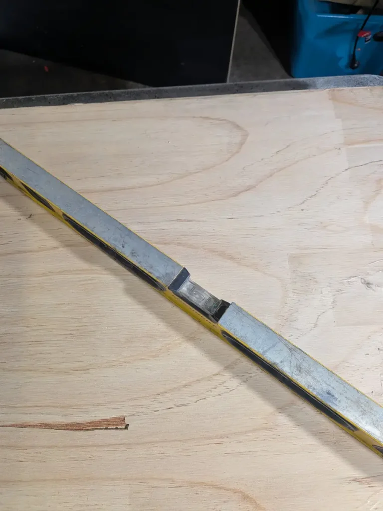 A spirit level laid across a plywood board to check the work surface is level before pouring resin coasters