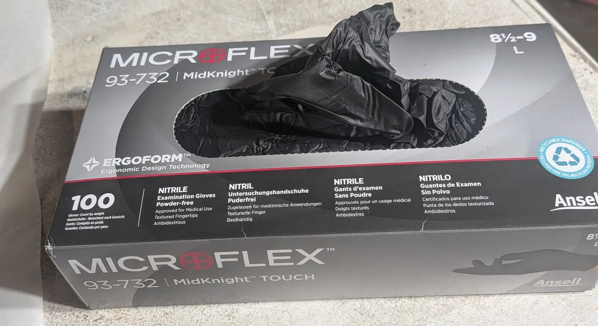 A box of black Microflex MidKnight Touch nitrile gloves, size large, on a workbench