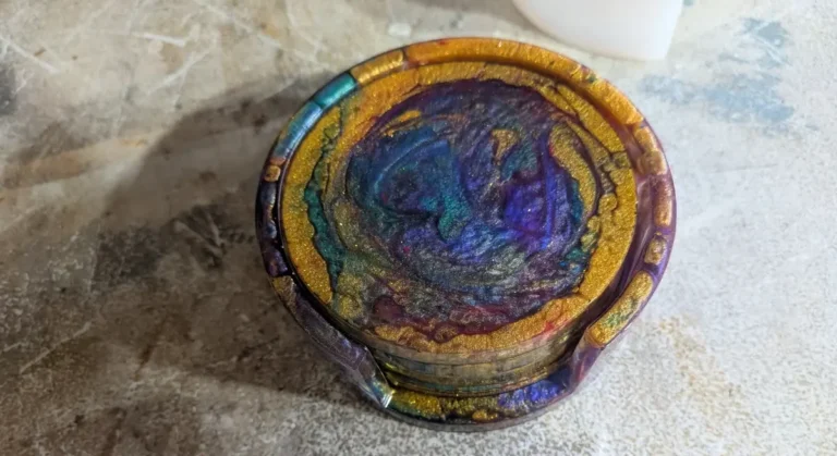 Four swirled purple, teal and gold epoxy resin coasters stacked in a matching resin holder, seen from above